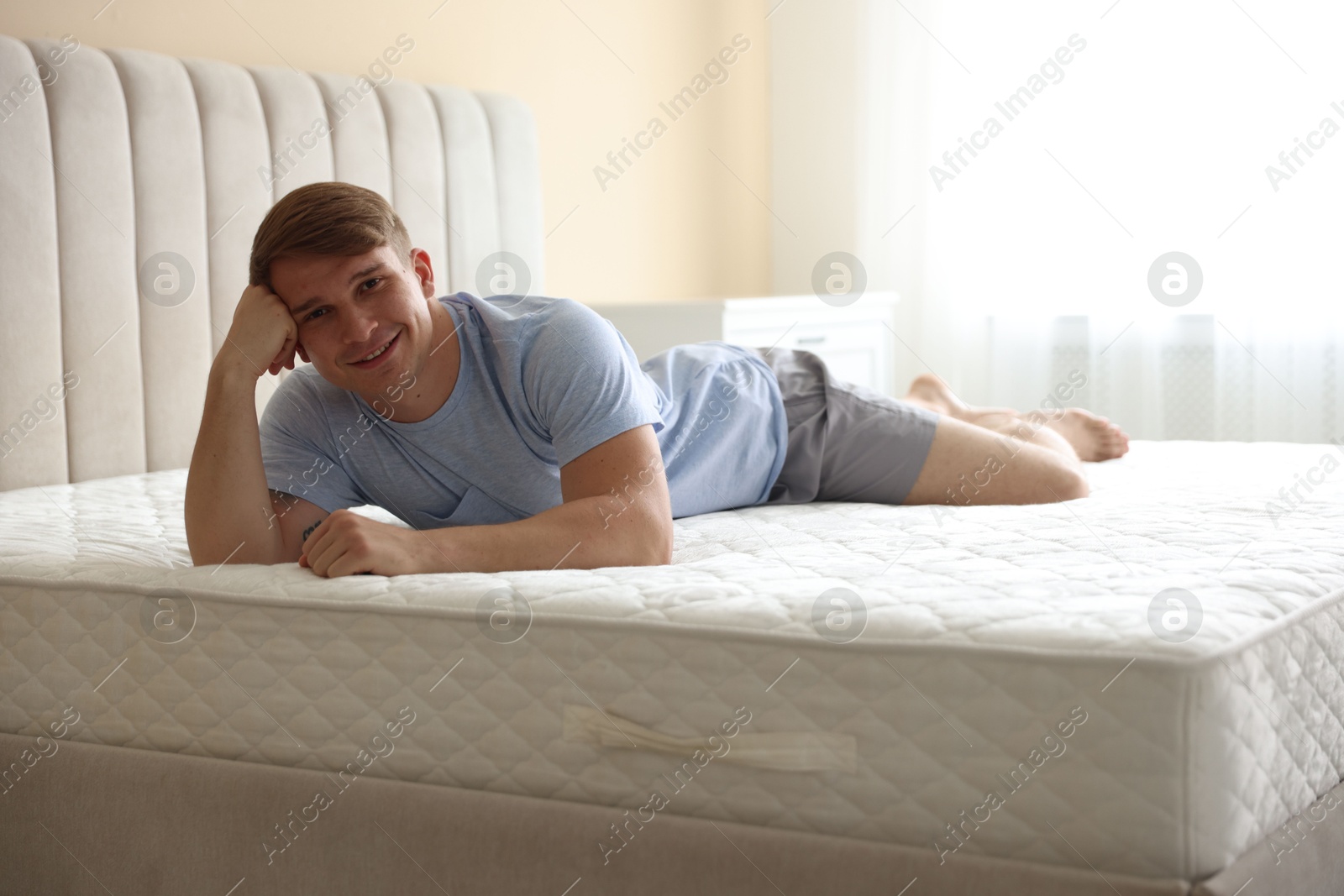 Young man lying on bed with soft mattress at home Photo of Young man lying on bed with soft mattress at home