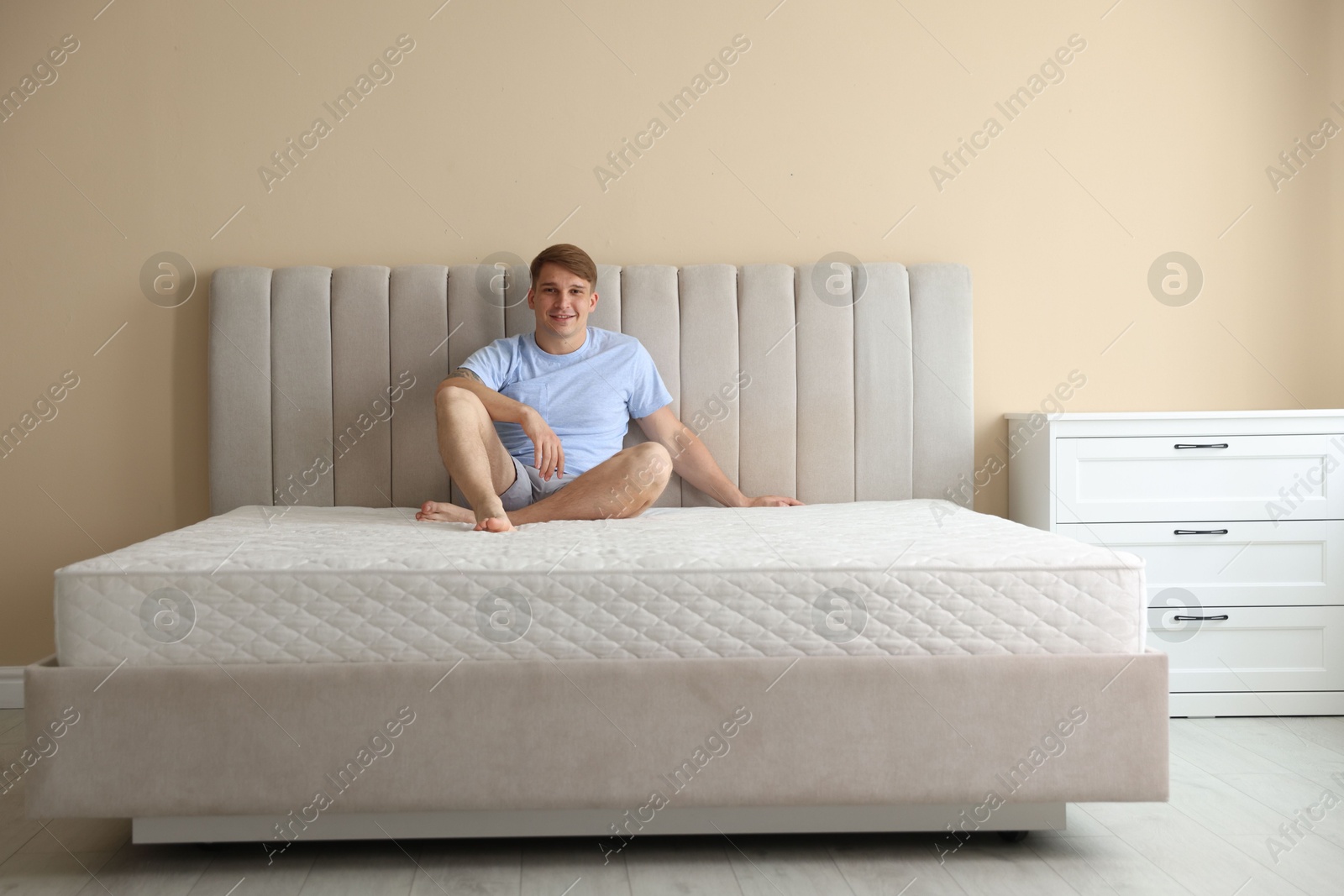 Young man sitting on bed with soft mattress at home Photo of Young man sitting on bed with soft mattress at home