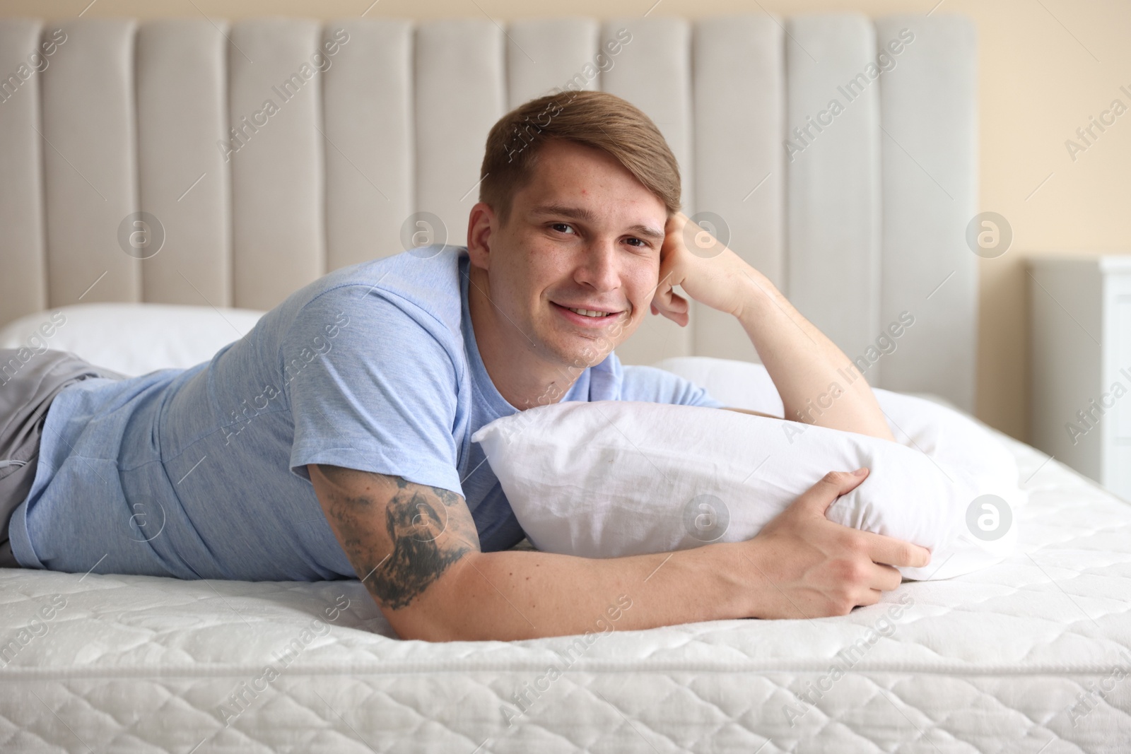 Young man lying on bed with soft mattress at home Photo of Young man lying on bed with soft mattress at home
