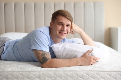 Photo of Young man lying on bed with soft mattress at home