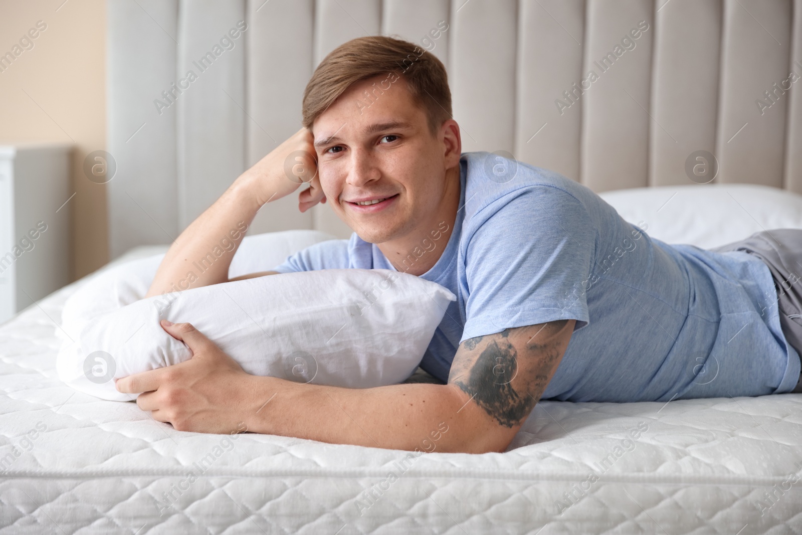 Young man lying on bed with soft mattress at home Photo of Young man lying on bed with soft mattress at home
