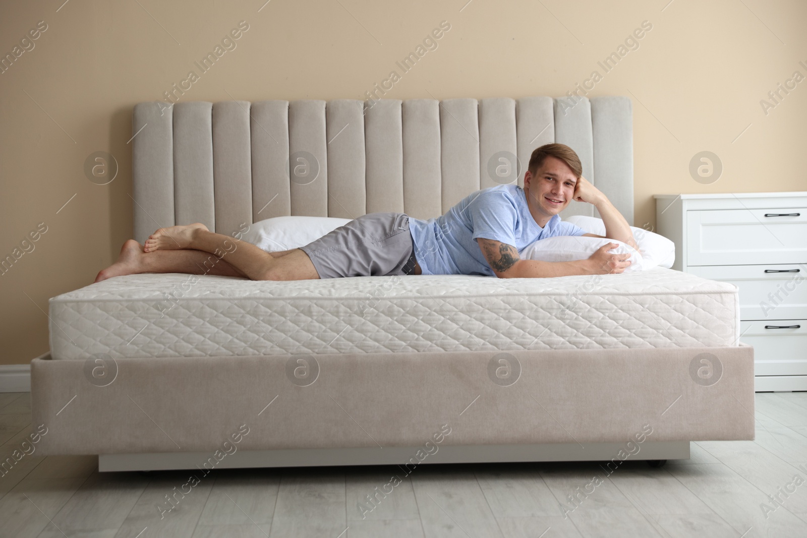 Young man lying on bed with soft mattress at home Photo of Young man lying on bed with soft mattress at home