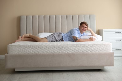 Photo of Young man lying on bed with soft mattress at home