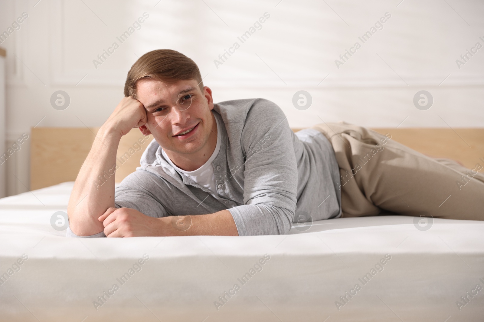 Young man lying on bed with soft mattress at home Photo of Young man lying on bed with soft mattress at home