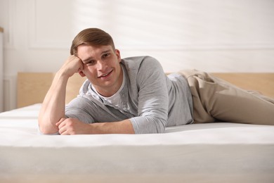 Photo of Young man lying on bed with soft mattress at home