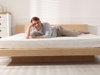 Photo of Young man lying on bed with soft mattress at home