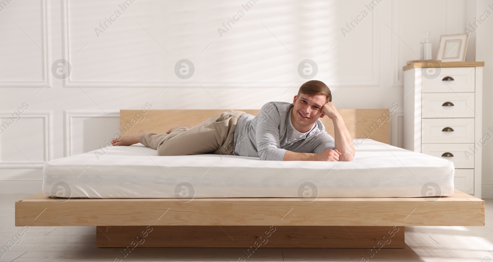Young man lying on bed with soft mattress at home Photo of Young man lying on bed with soft mattress at home