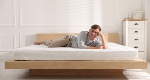 Photo of Young man lying on bed with soft mattress at home