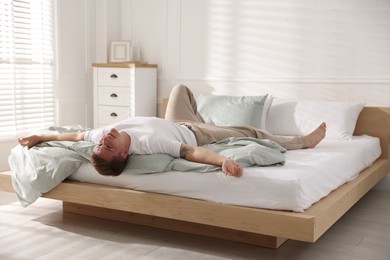 Photo of Young man lying on bed with soft mattress at home