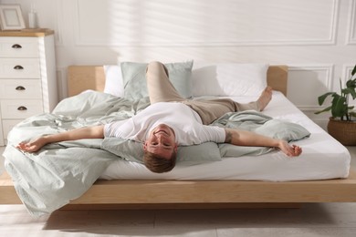 Photo of Young man lying on bed with soft mattress at home