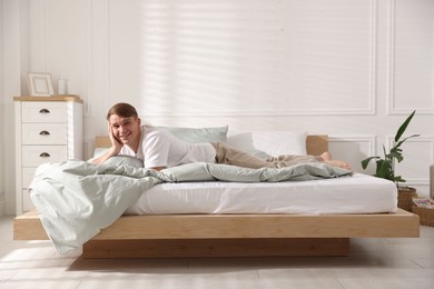 Photo of Young man lying on bed with soft mattress at home
