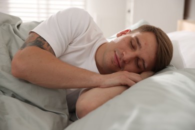 Photo of Young man sleeping on bed with soft mattress at home