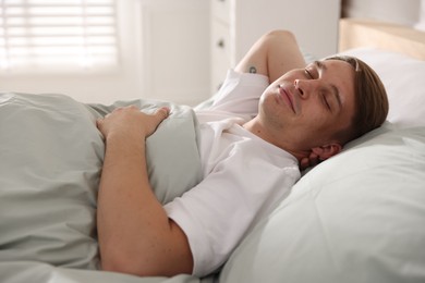 Photo of Young man sleeping on bed with soft mattress at home