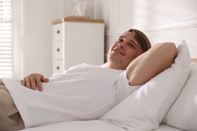 Photo of Young man lying on bed with soft mattress at home