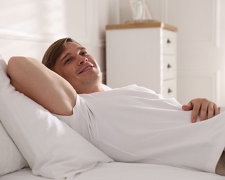Photo of Young man lying on bed with soft mattress at home