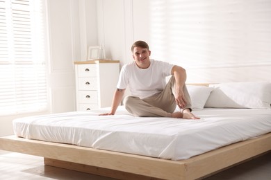 Photo of Young man lying on bed with soft mattress at home