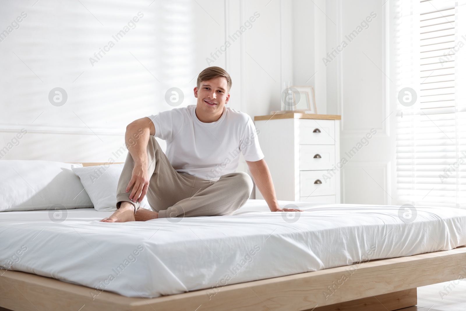 Young man lying on bed with soft mattress at home Photo of Young man lying on bed with soft mattress at home