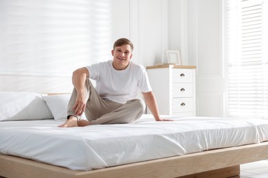 Photo of Young man lying on bed with soft mattress at home