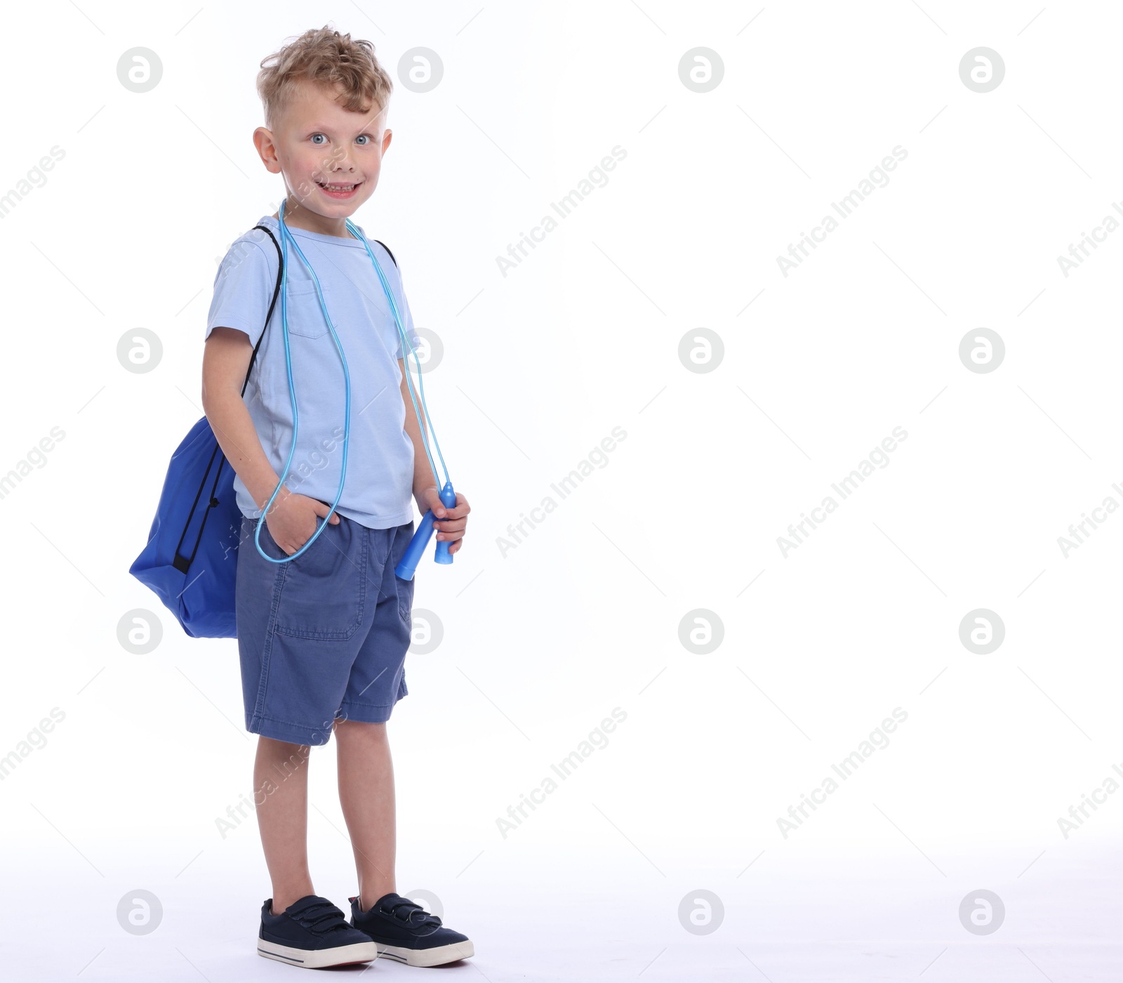Little boy with jump rope and sports string bag on white background, space for text Photo of Little boy with jump rope and sports string bag on white background, space for text