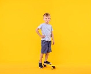 Photo of Little boy with penny board on yellow background