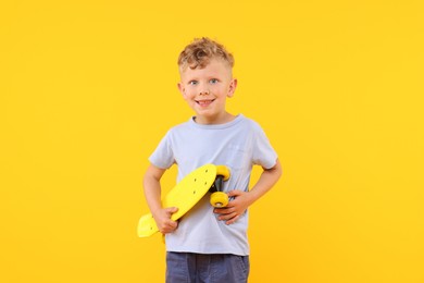 Photo of Little boy with penny board on yellow background