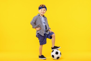 Photo of Little boy with soccer ball on yellow background