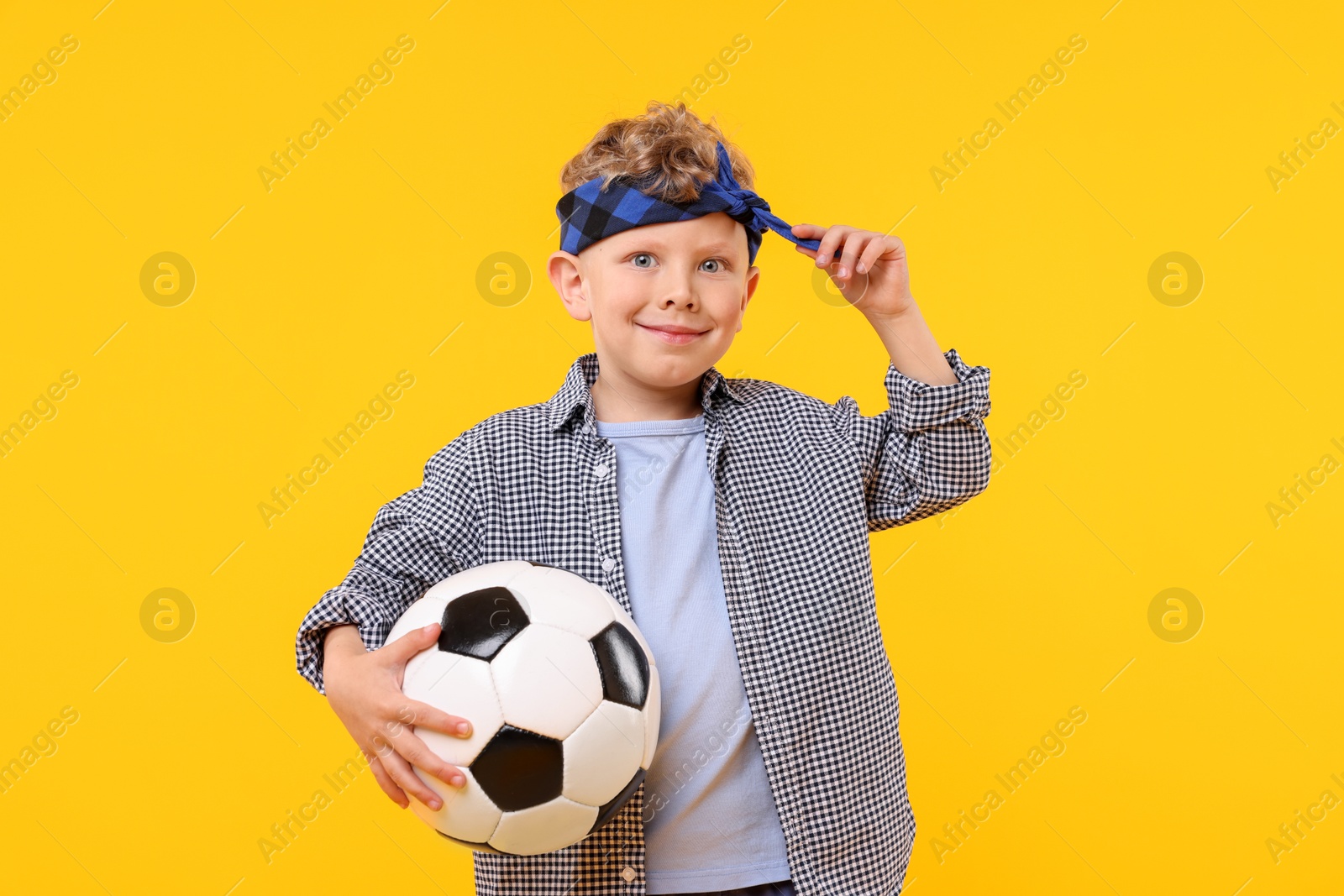 Little boy with soccer ball on yellow background Photo of Little boy with soccer ball on yellow background