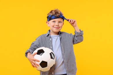 Photo of Little boy with soccer ball on yellow background