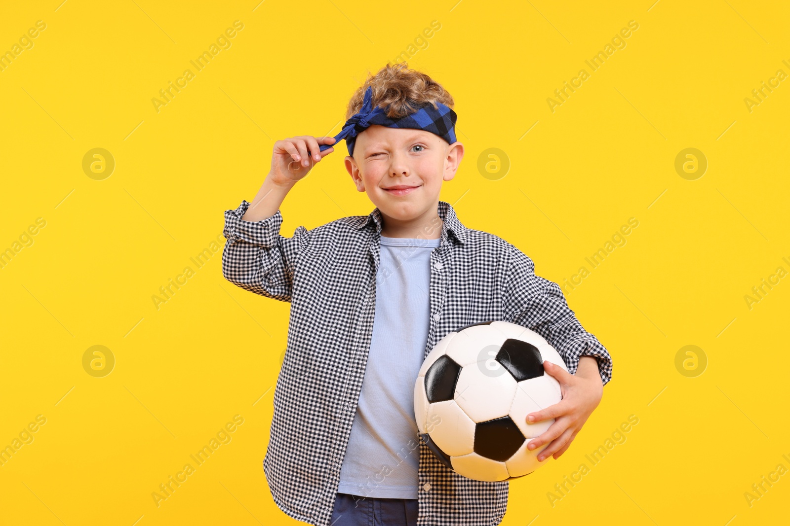 Little boy with soccer ball on yellow background Photo of Little boy with soccer ball on yellow background