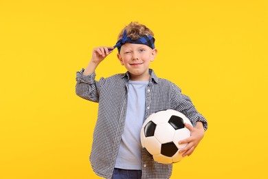 Photo of Little boy with soccer ball on yellow background