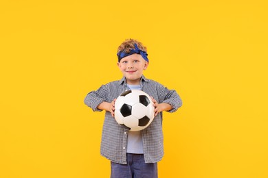 Photo of Little boy with soccer ball on yellow background