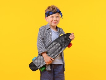 Photo of Little boy with penny board on yellow background