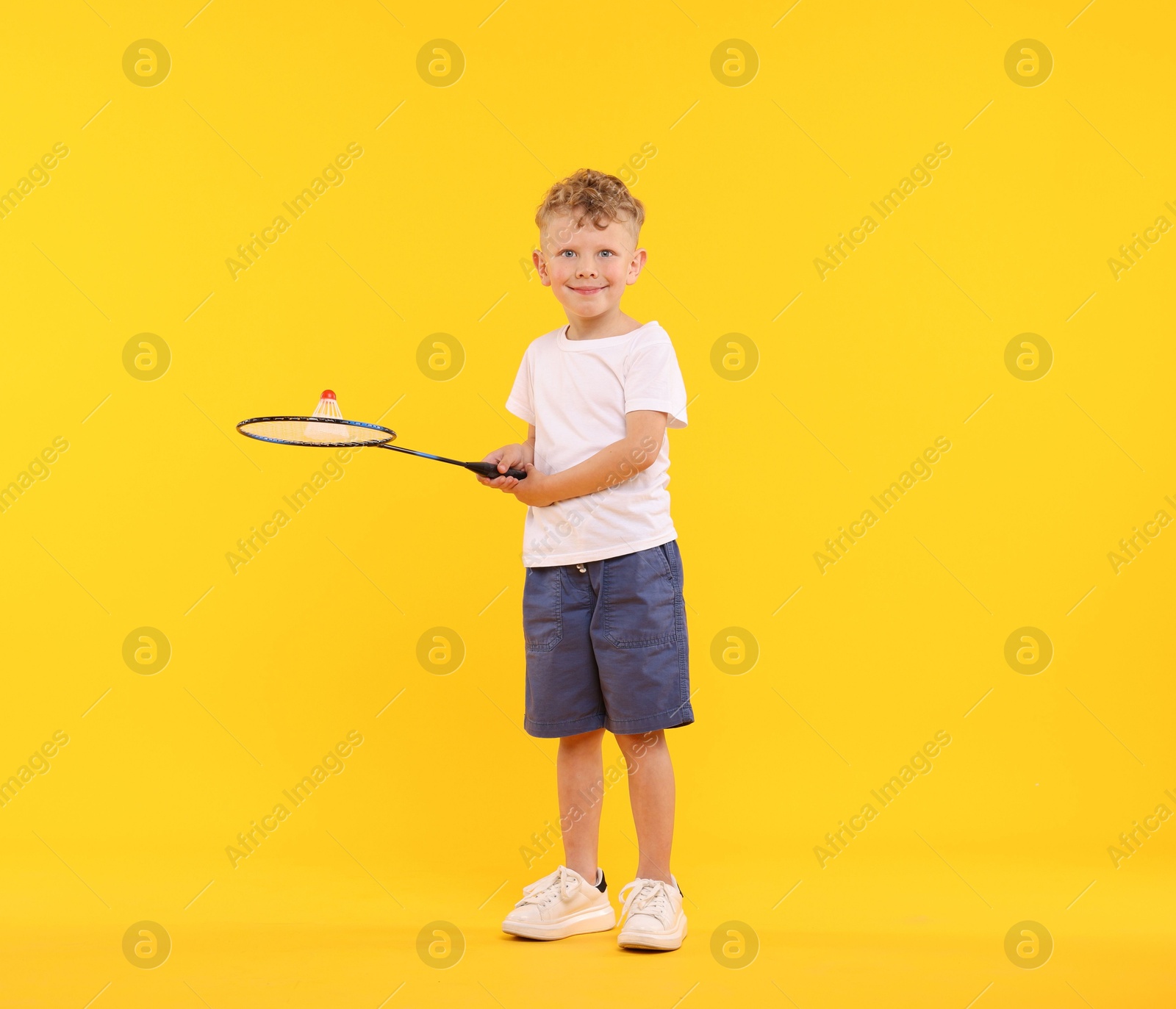 Little boy with badminton racket and shuttlecock on yellow background Photo of Little boy with badminton racket and shuttlecock on yellow background