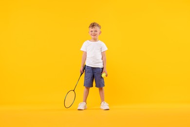 Photo of Little boy with racket and tennis ball on yellow background
