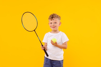 Photo of Little boy with racket and tennis ball on yellow background