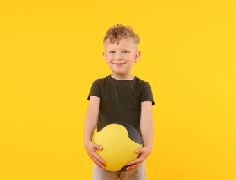 Photo of Little boy with medicine ball on yellow background