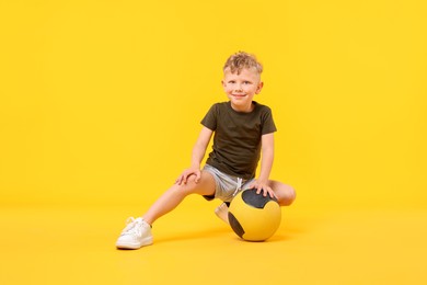 Photo of Little boy with medicine ball on yellow background