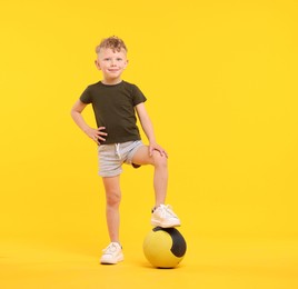 Photo of Little boy with medicine ball on yellow background