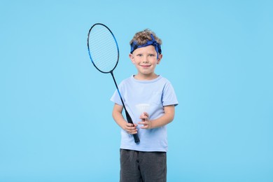Photo of Little boy with badminton racket and shuttlecock on light blue background