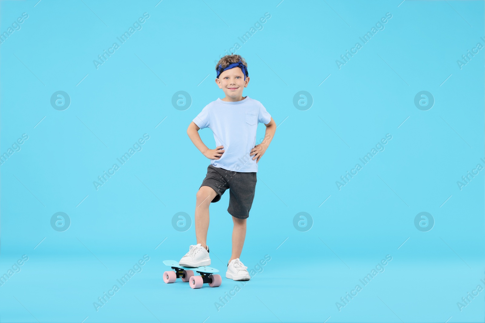 Little boy with penny board on light blue background Photo of Little boy with penny board on light blue background