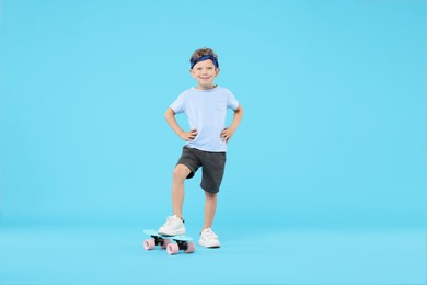 Photo of Little boy with penny board on light blue background