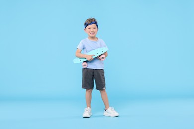 Photo of Little boy with penny board on light blue background