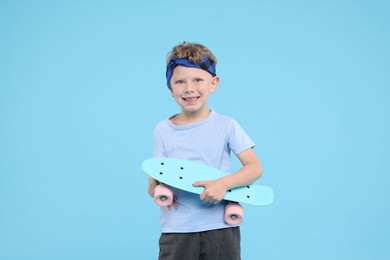 Photo of Little boy with penny board on light blue background