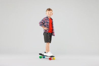 Photo of Little boy standing on penny board against gray background
