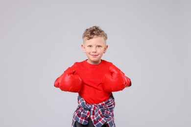 Photo of Little boy with boxing gloves on gray background