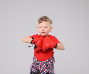 Photo of Little boy with boxing gloves on gray background