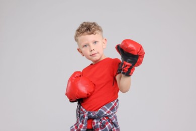 Photo of Little boy with boxing gloves on gray background