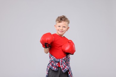 Photo of Little boy with boxing gloves on gray background