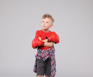 Photo of Little boy with boxing gloves on gray background
