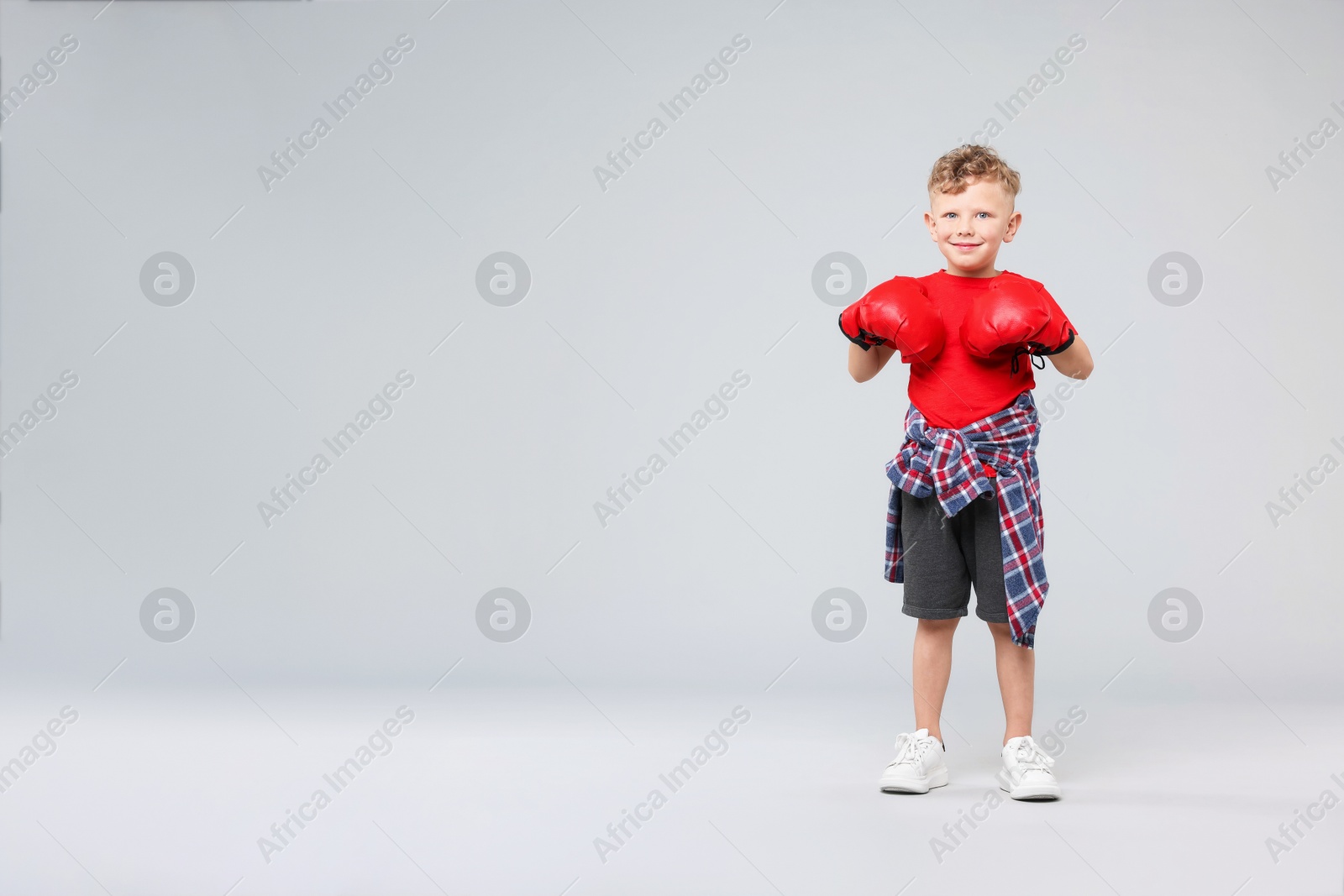 Little boy with boxing gloves on gray background, space for text Photo of Little boy with boxing gloves on gray background, space for text